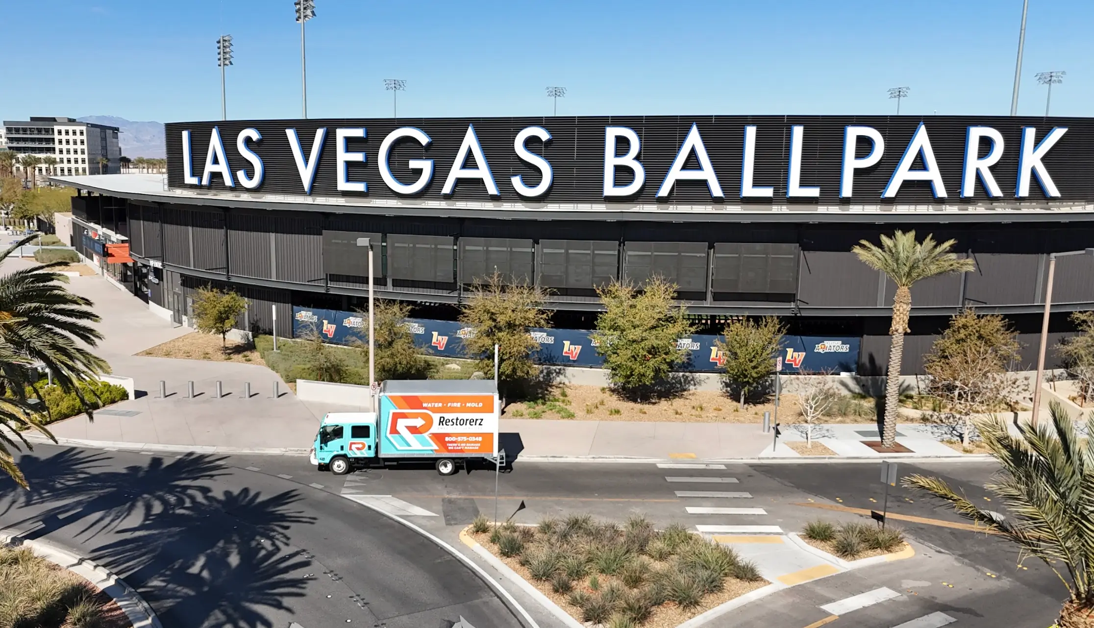 A Restorerz truck drives past the entrance of Las Vegas Ballpark on a sunny day.